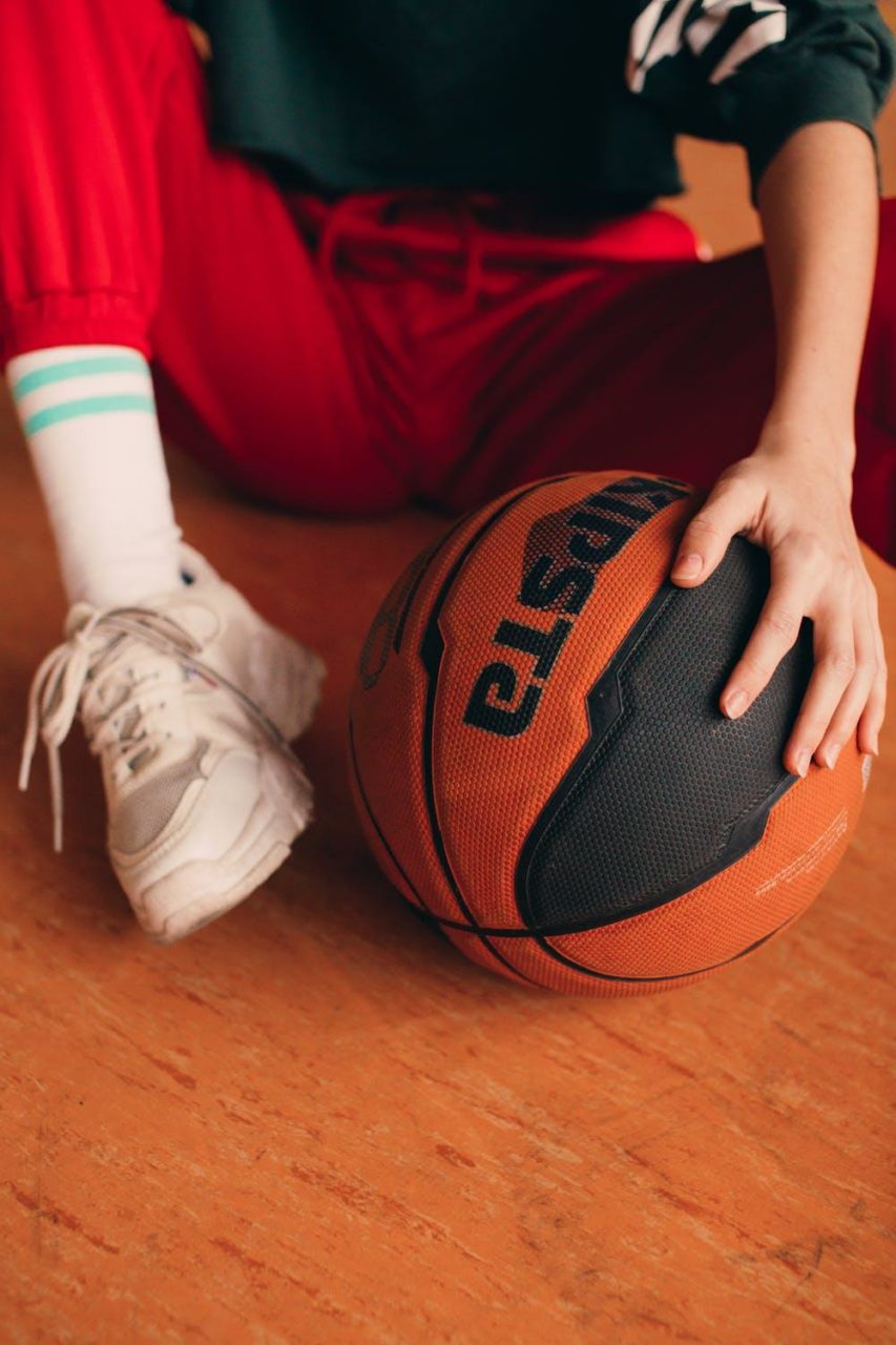 A basketball player poses next to a ball while on the ground.