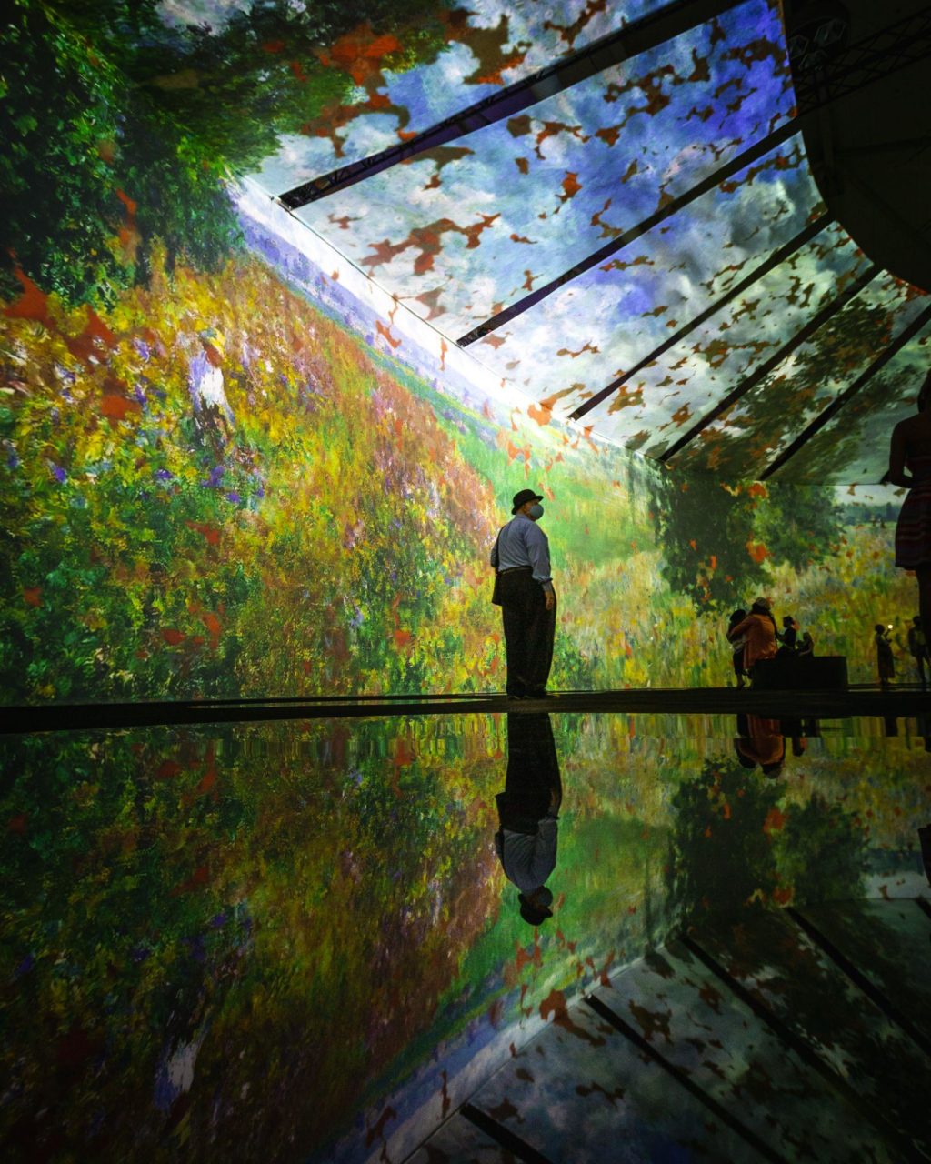 Beyond Monet Un hombre se para en medio de la exposición inmersiva que presenta las pinturas de Monet.