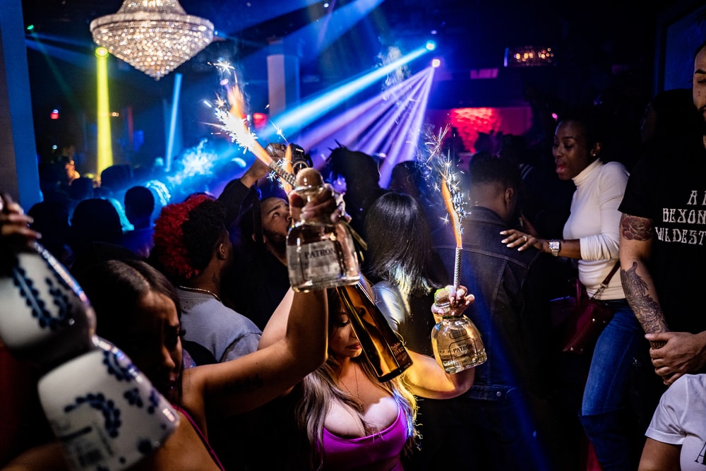 A Couple of Women Waving Firecrackers and a Bottle of Booze While Dancing at a Party