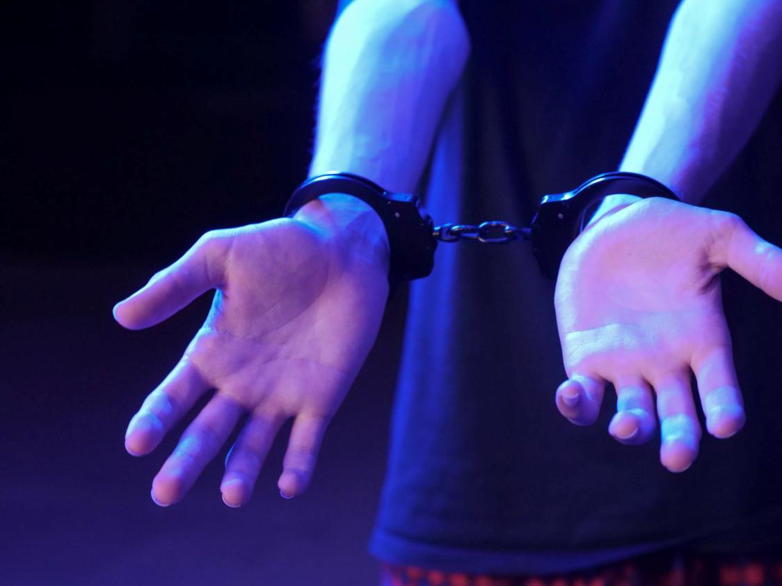 A person's hands with handcuffs placed on them.