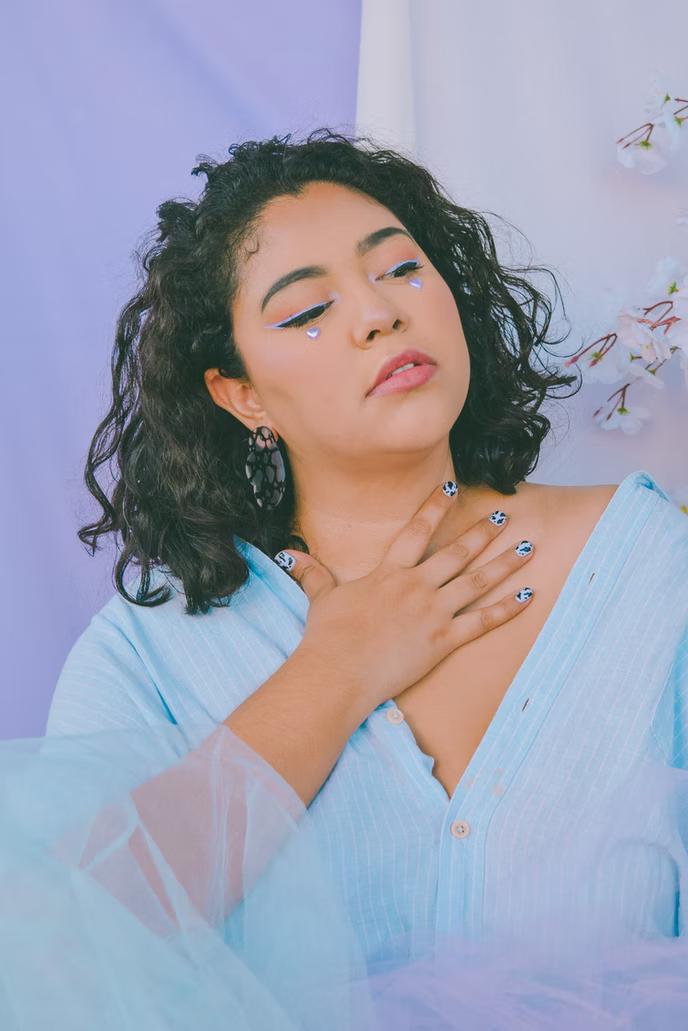 una mujer de tallas grandes con un hermoso top azul y maquillaje editorial.