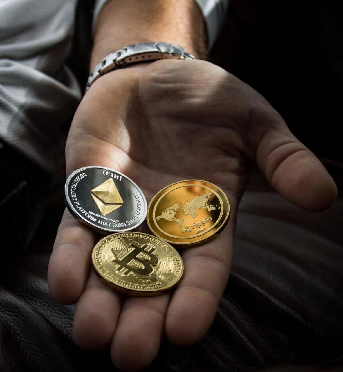Varias monedas de criptomonedas imaginarias colocadas en la palma de la mano de alguien.