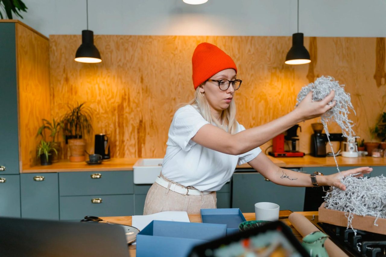 Una madre emprendedoras que trabaja en casa empaca un pedido con relleno.