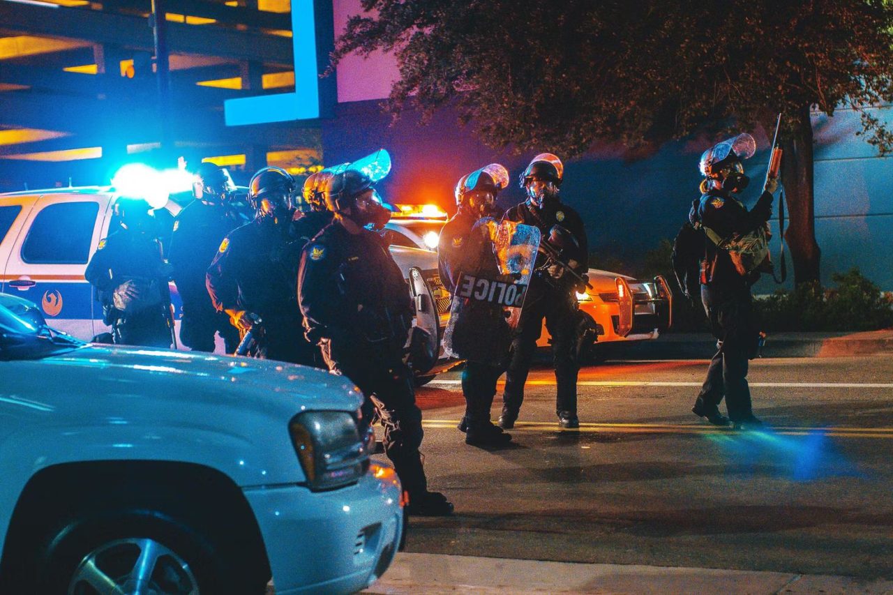 A group of police officers in full gear gathered outside a crime scene.