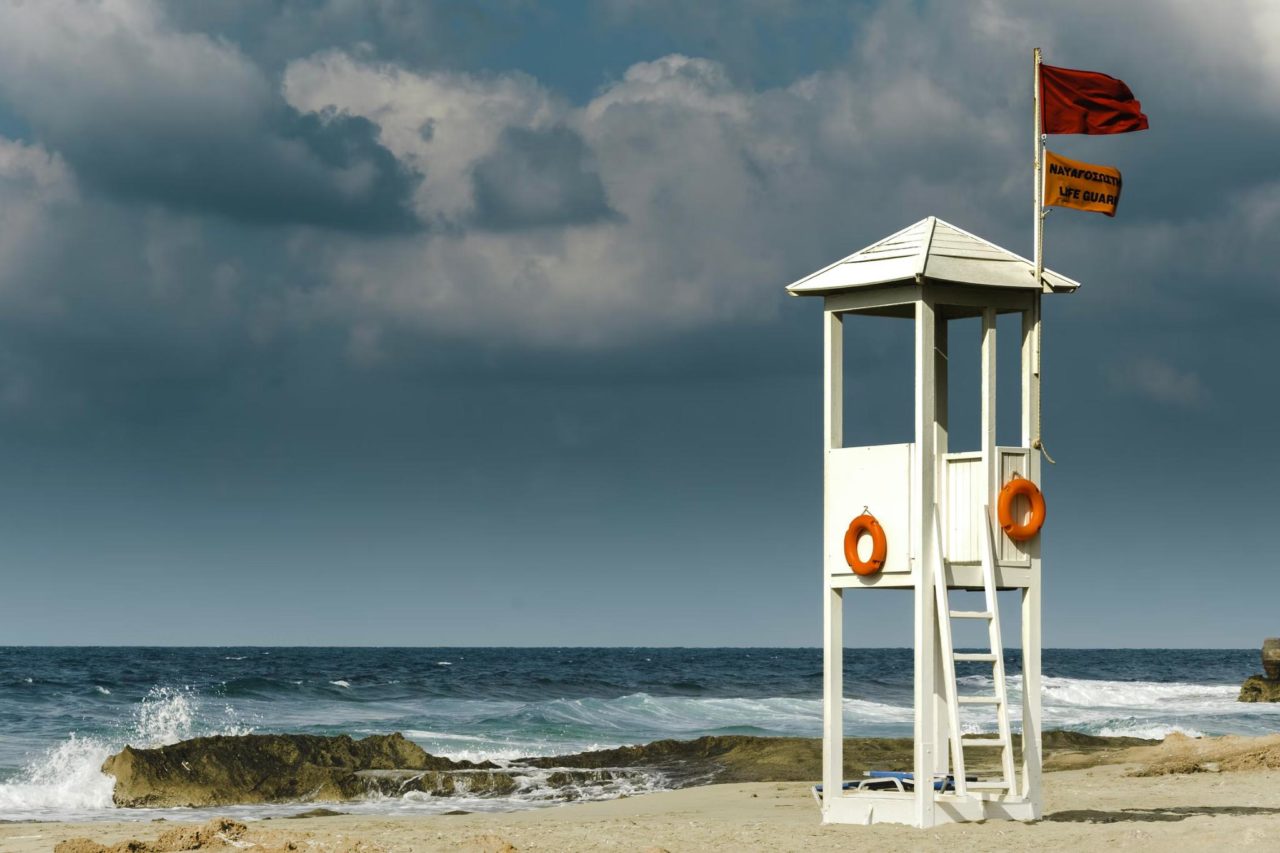 una torre de salvavidas en una playa local con una bandera roja para emitir advertencias.