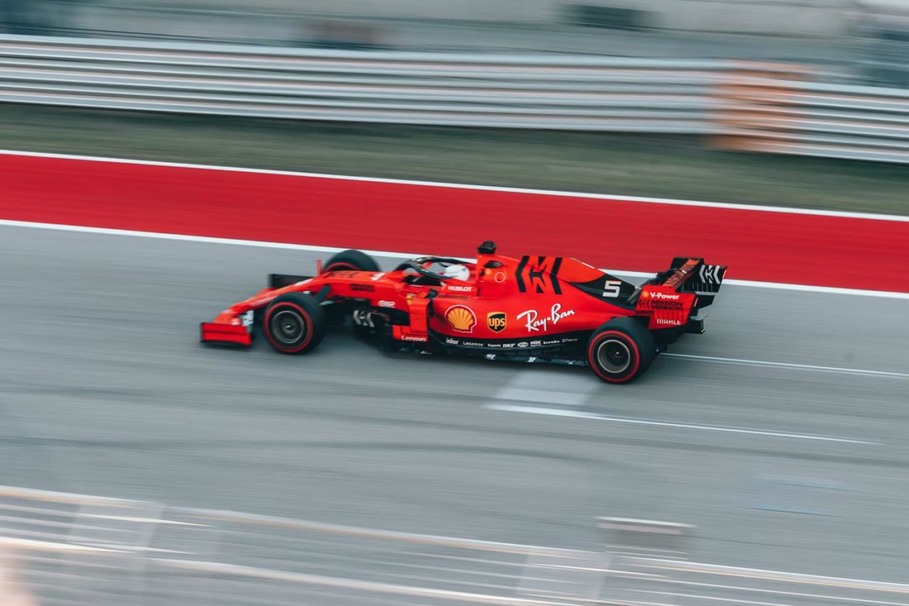 A bright red F1 speeds past on a track.