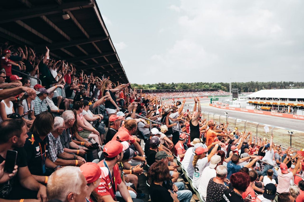 una gran multitud sentada en la audiencia vitorea con entusiasmo durante un evento de F1.