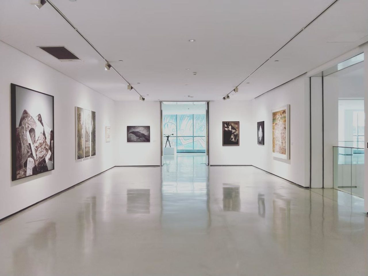 A well-lit, empty gallery with artwork on the walls.