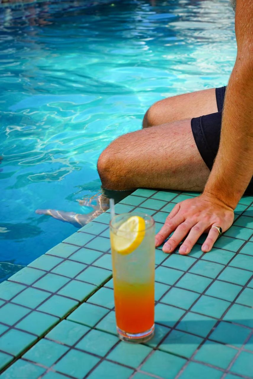 Un hombre pasa el rato junto a una piscina en Miami, con un vaso a su lado.