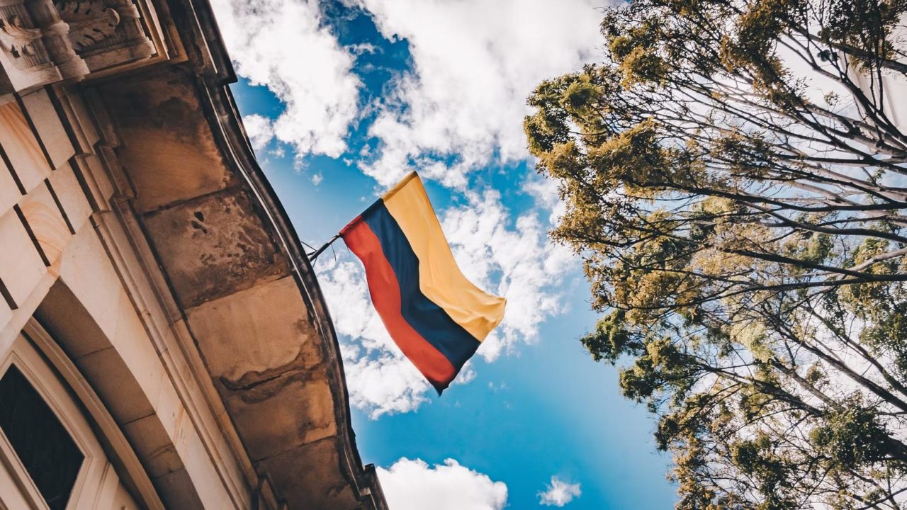 A Colombian flag flying in the wind on a building.
