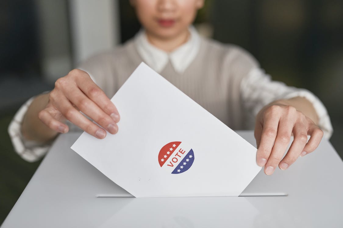 A person inserting a ballot in a white box.