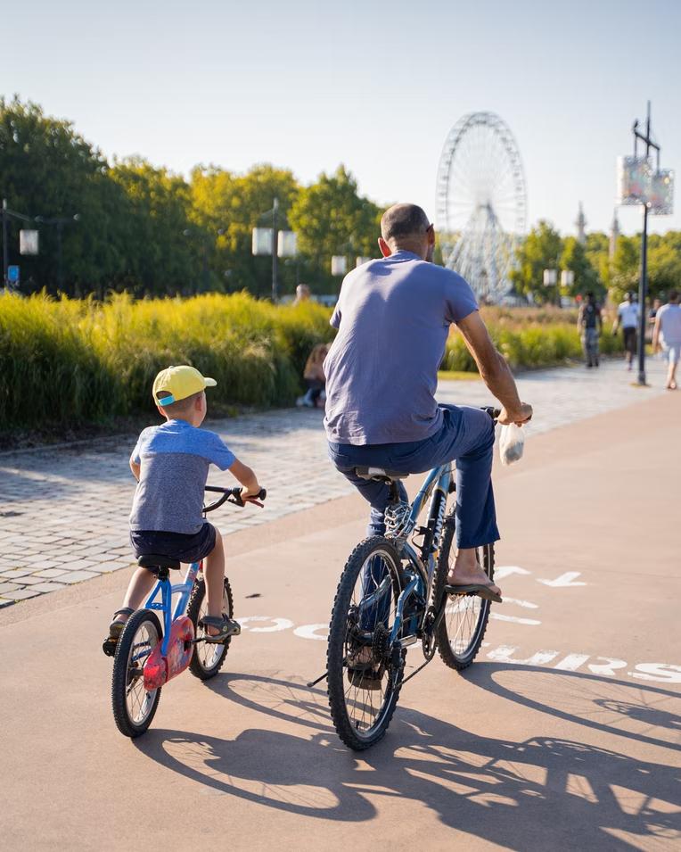 A father and son cycling outdoors along a path.