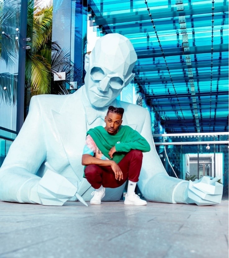 una persona agachada frente a una estatua blanca.