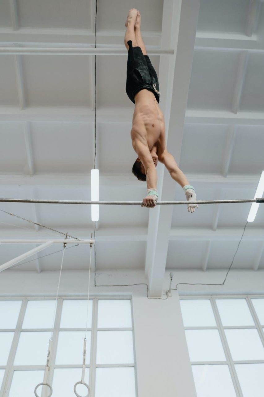 una gimnasta gira boca abajo en una barra.