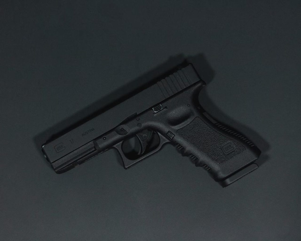 A handheld Glock placed on a black surface.