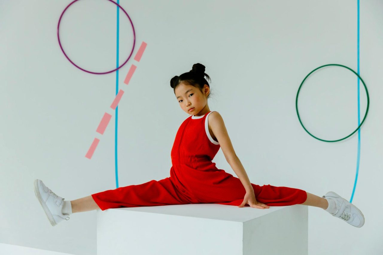 A young girl performs a split while on a block.