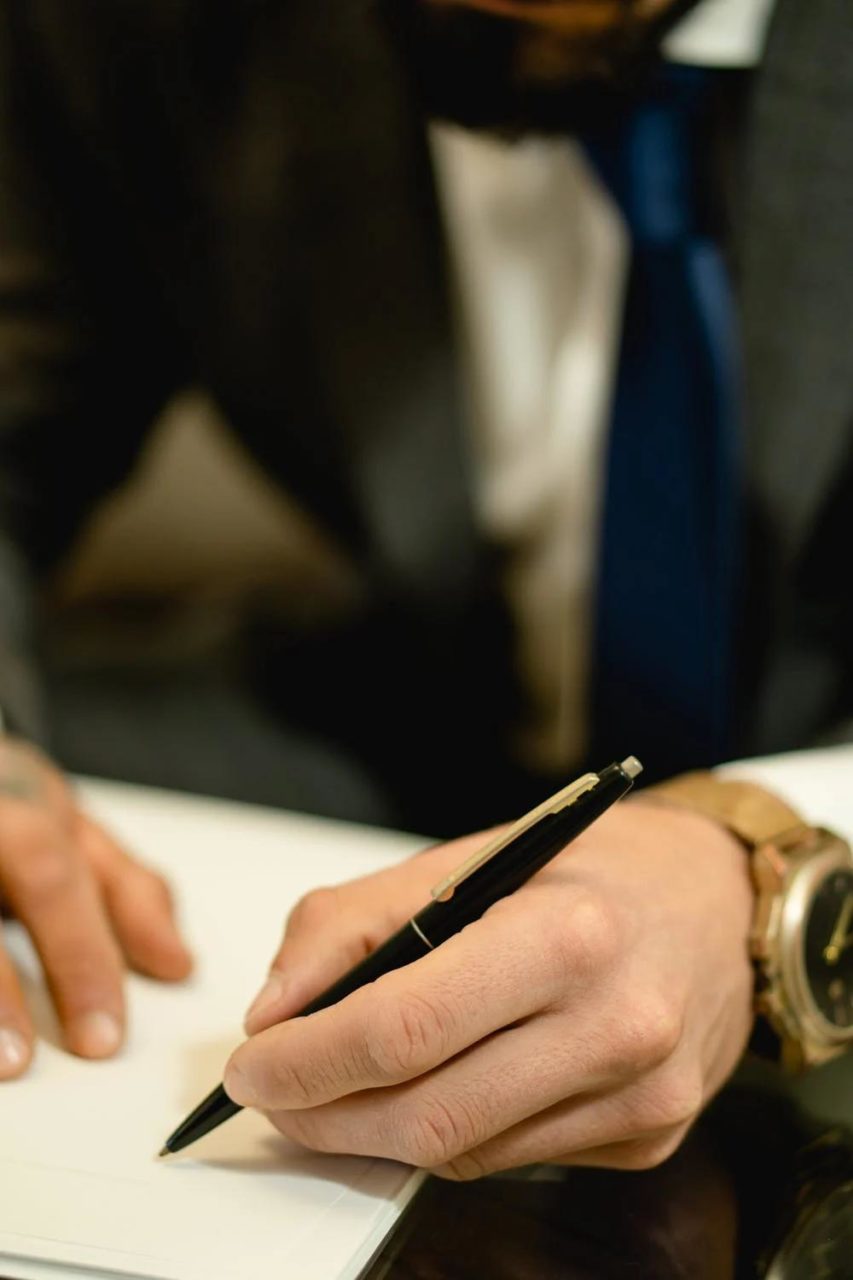 A closeup of an official holding a pen and signing a document.