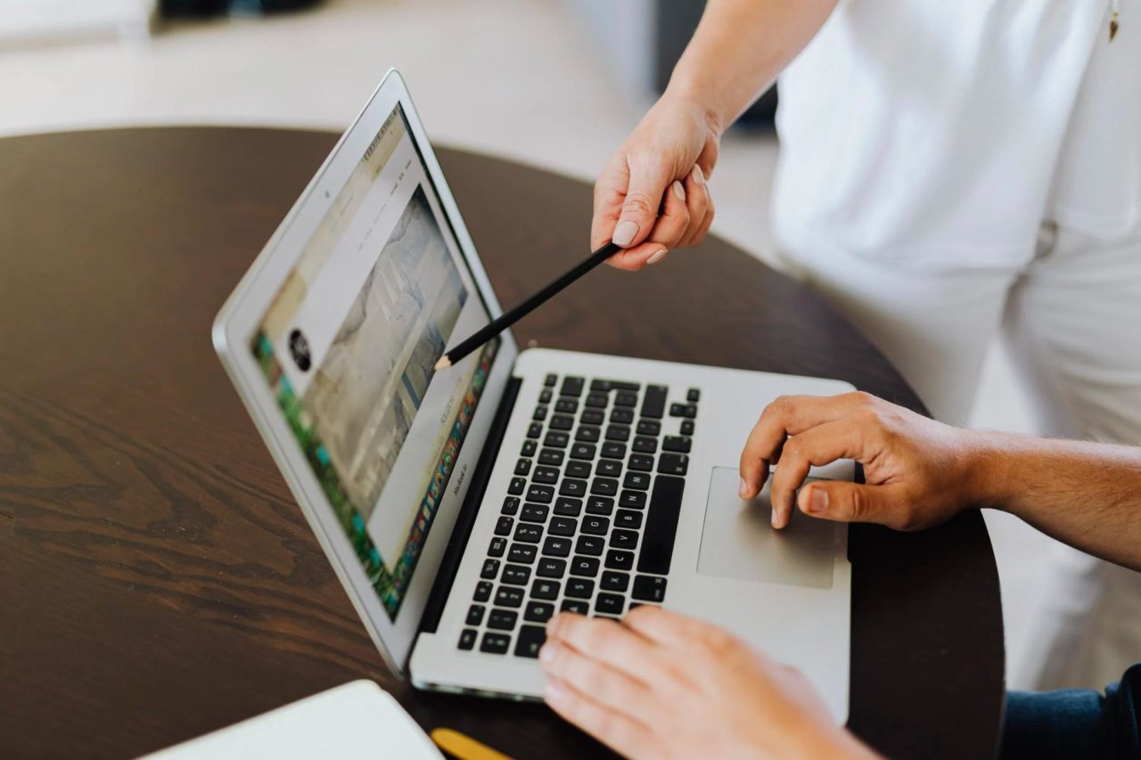 A tech company employee works on their laptop with their coworker.