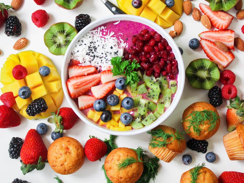 A bowl of fruit surrounded by colorful fruits.
