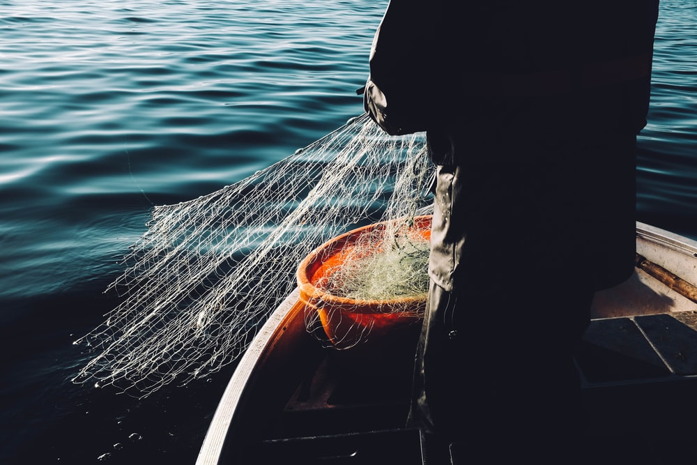 A person releasing a fishnet into the sea.