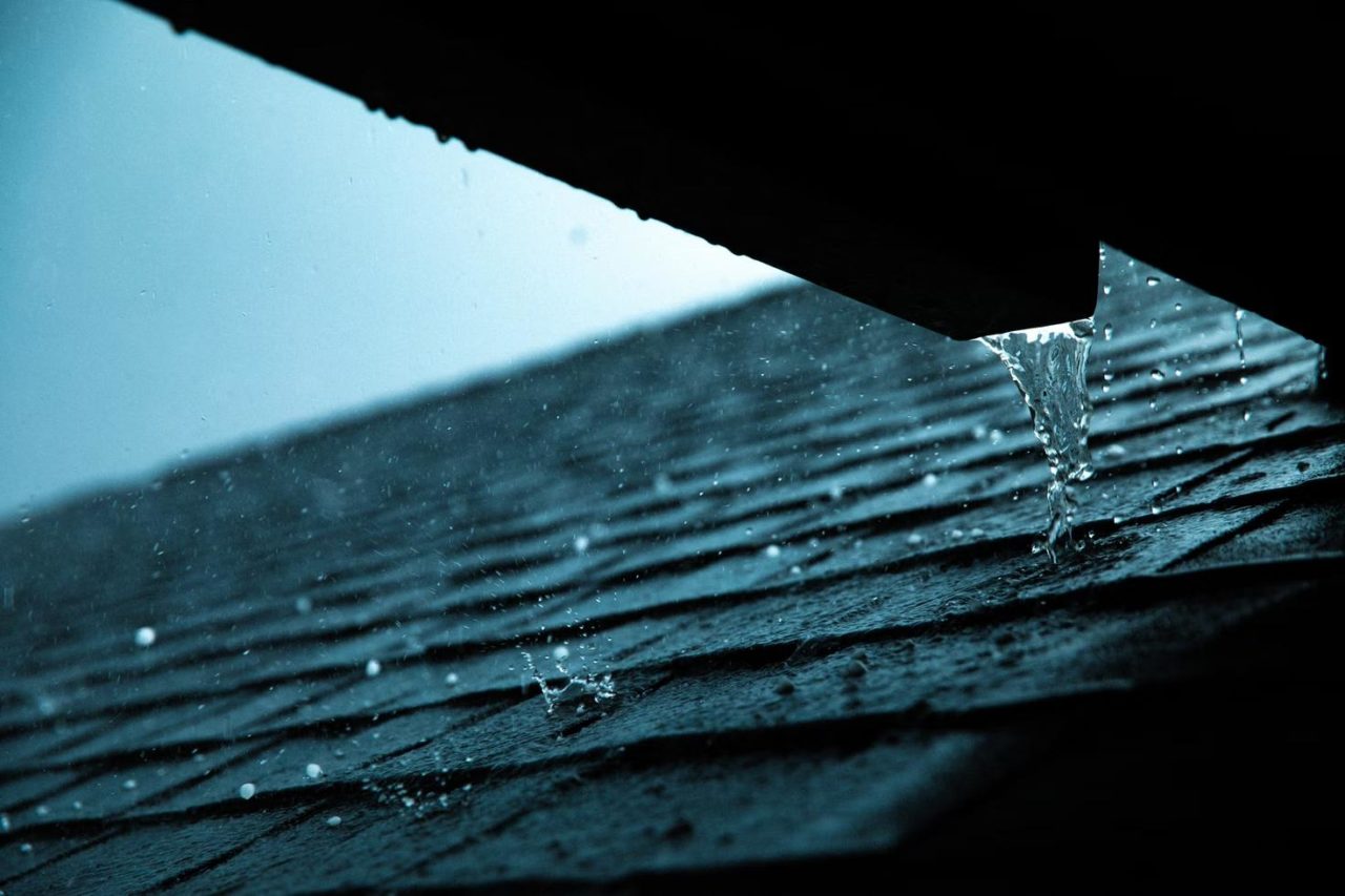 A protected roof with rainwater pouring down it.