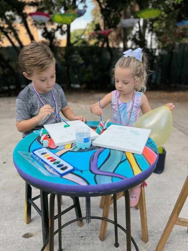 dos niños sentados usando suministros de pintura.