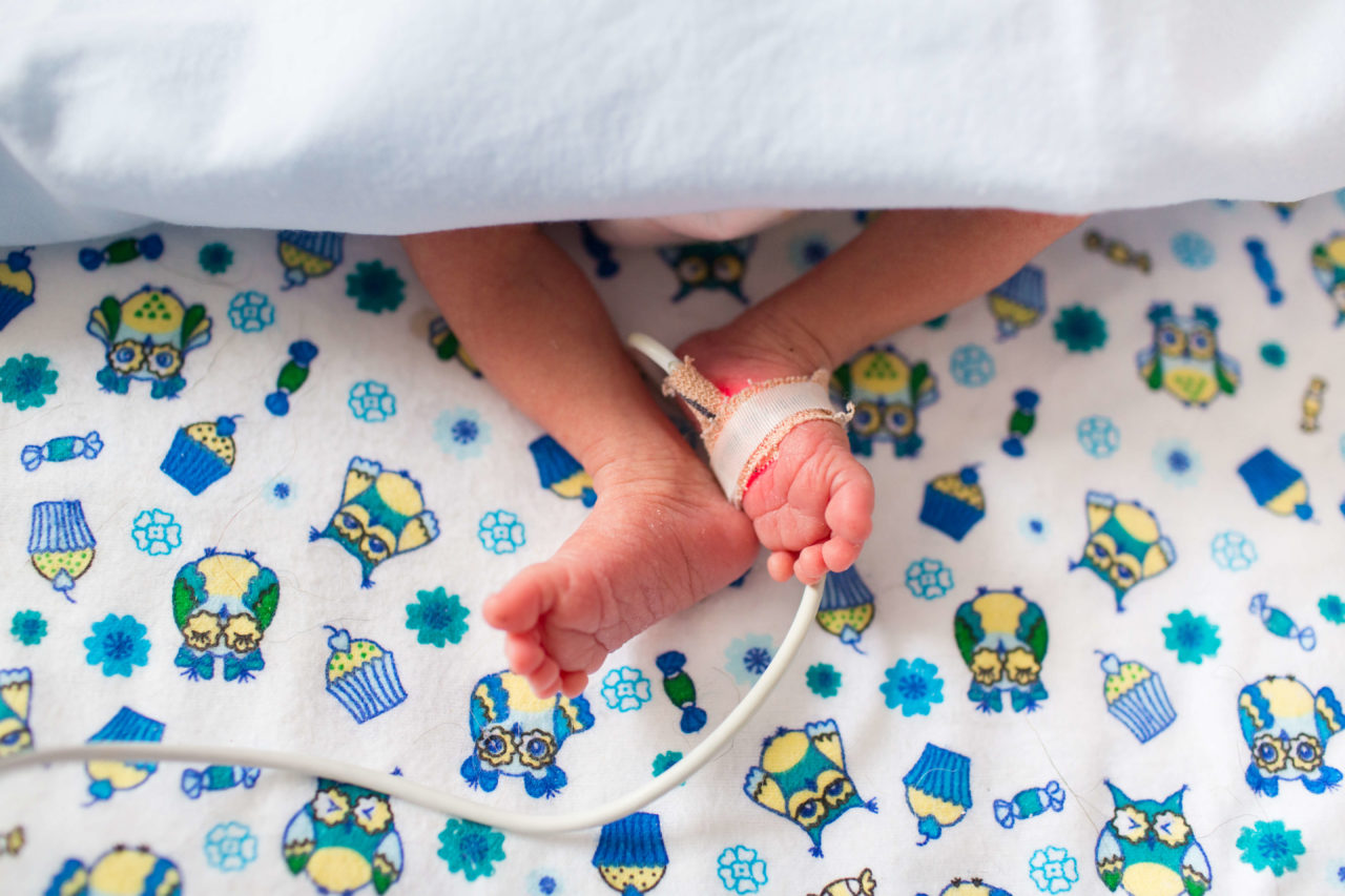 Bebé prematura y cerca de sus pies en manos de humanos.