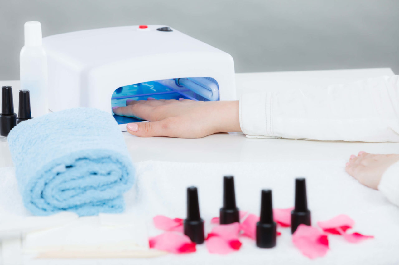 Mano de mujer en una manicura de gel de secado con lámpara led uv