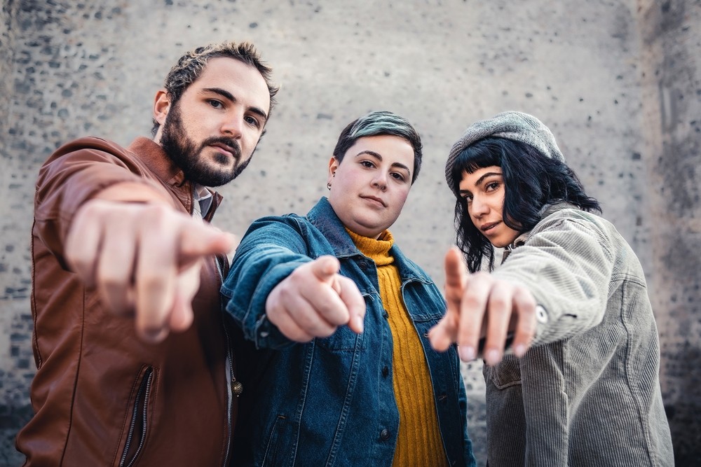 Cheerful group of people pointing and looking at the camera outdoors