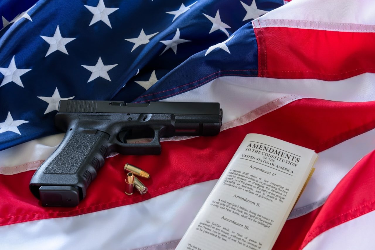 A gun next to a document on top of the US flag