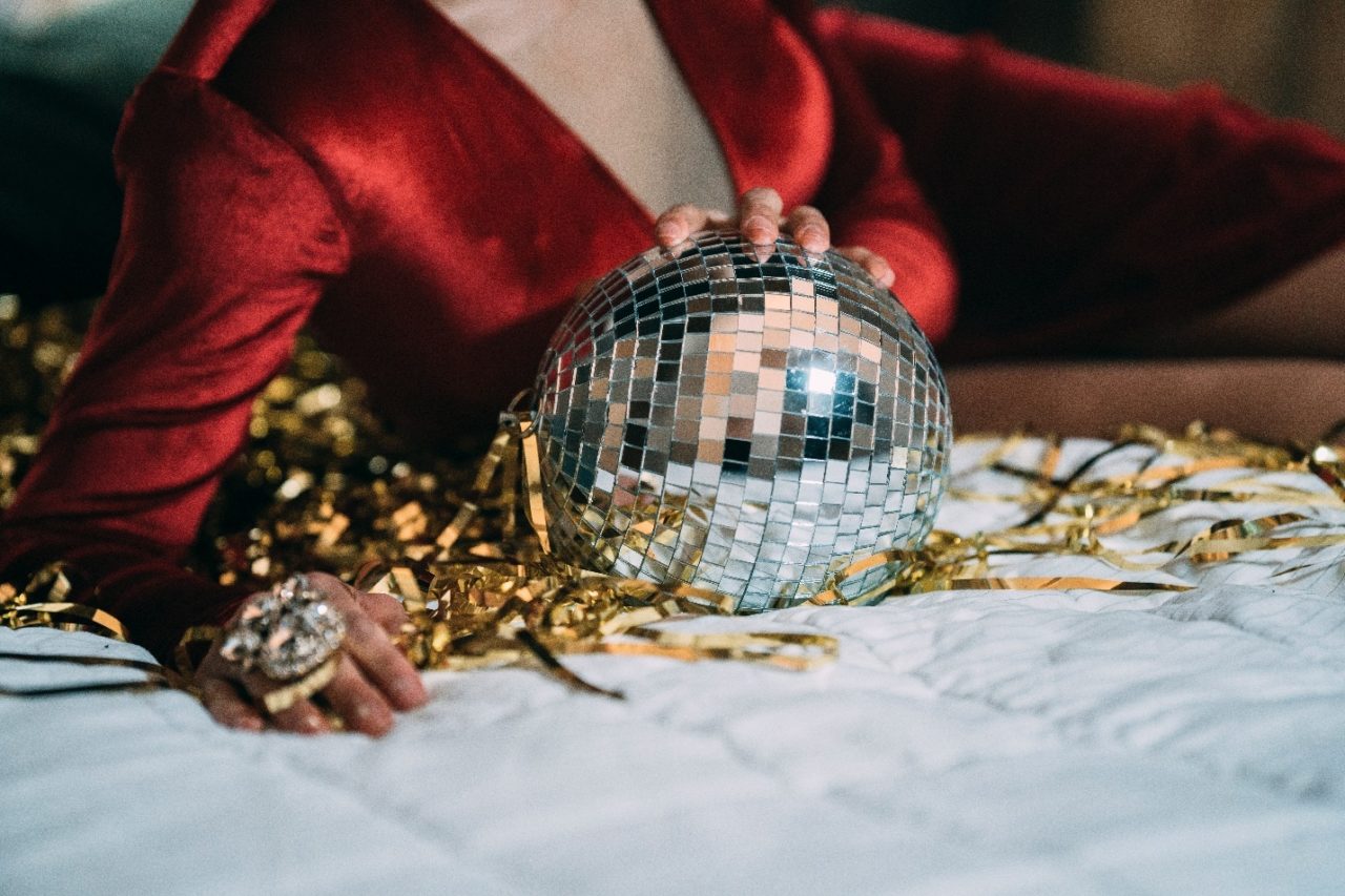 A drag queen holding a disco ball