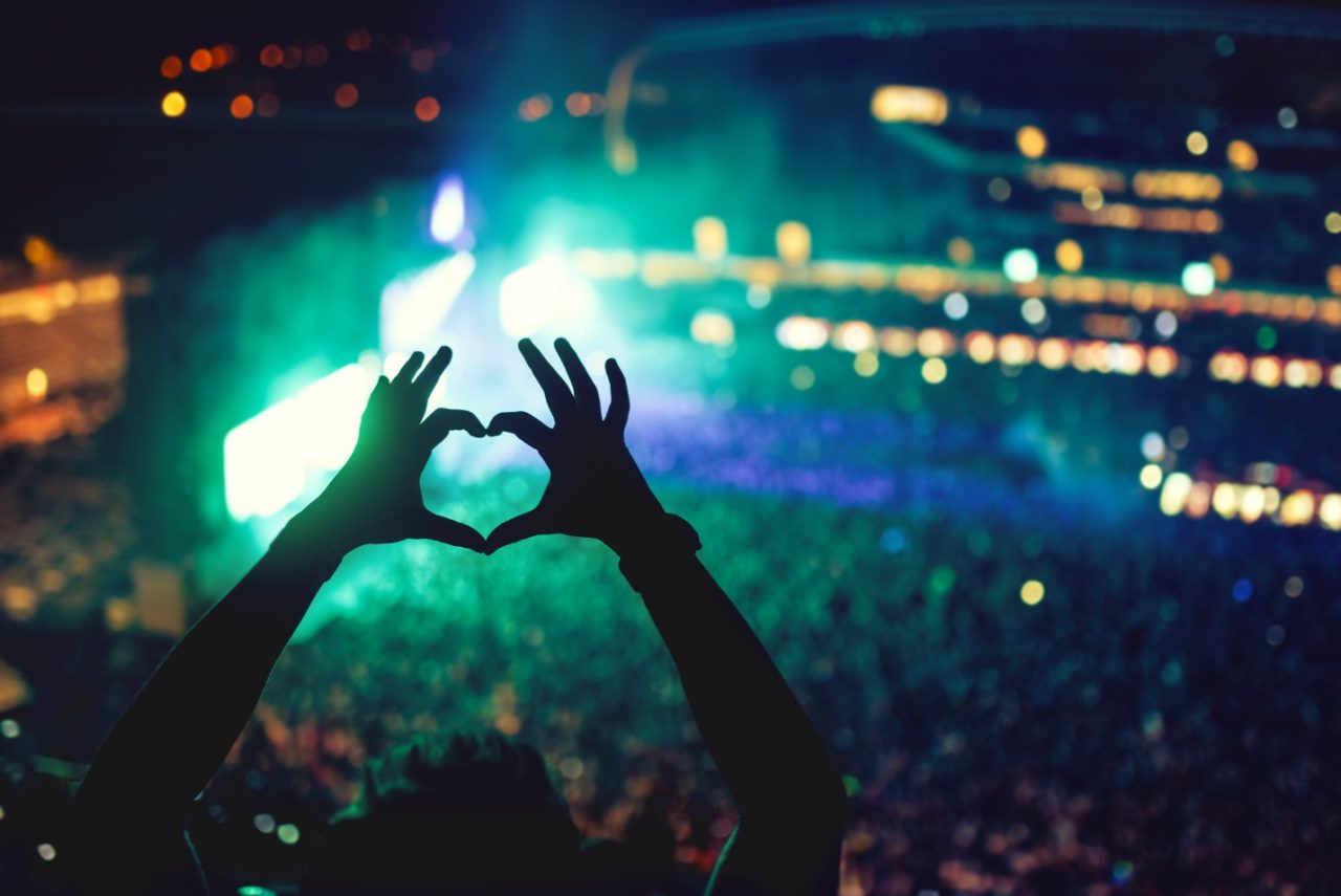 A pair of hands joined in a heart shape during a music festival