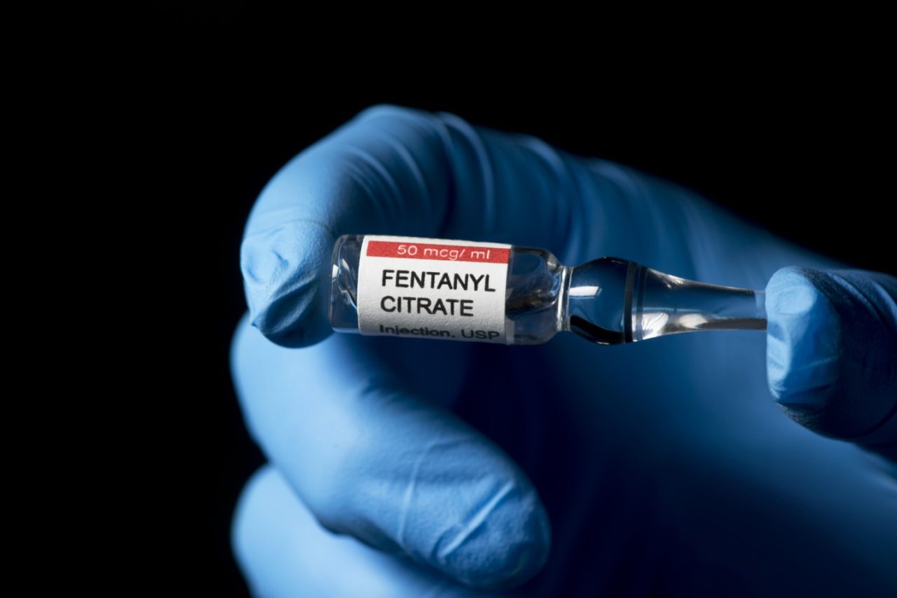 A gloved hand holding a fentanyl vial