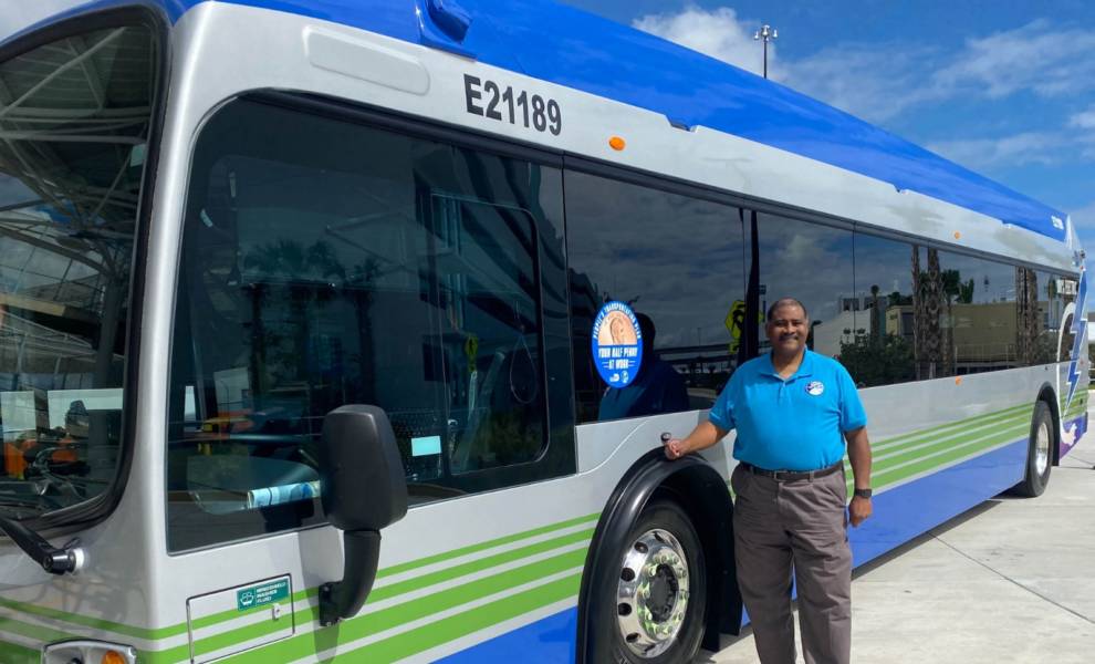 Oscar Branyon posa para una foto frente a un autobús