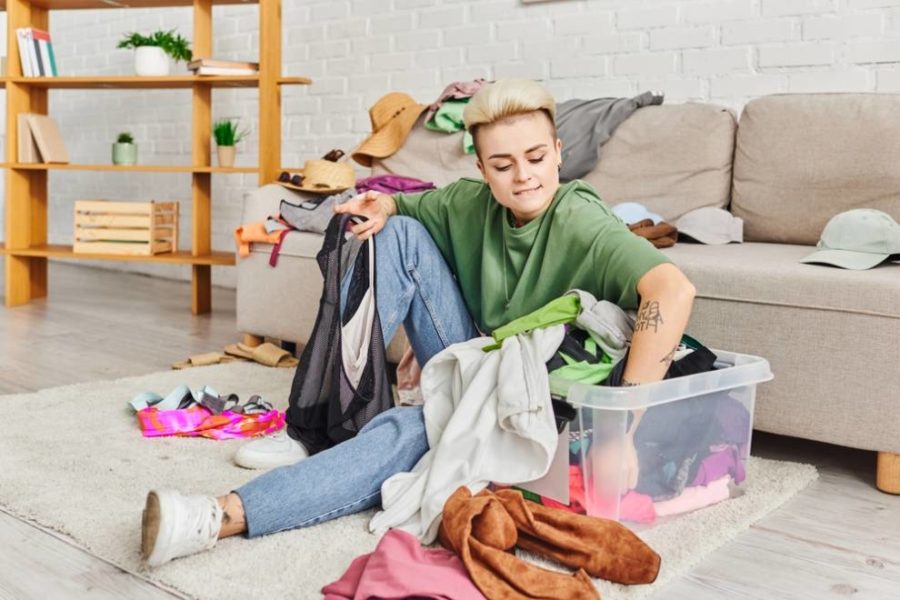 Persona sacando la ropa de la cesta mientras está sentada en el suelo