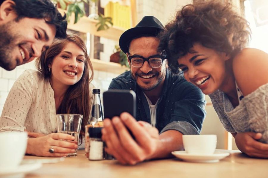 un grupo de amigos sonriendo y mirando un teléfono
