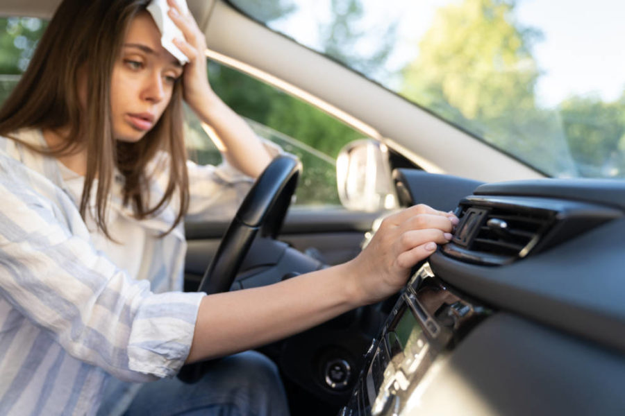 Mujeres sintiendo calor dentro del auto y encendiendo el aire acondicionado