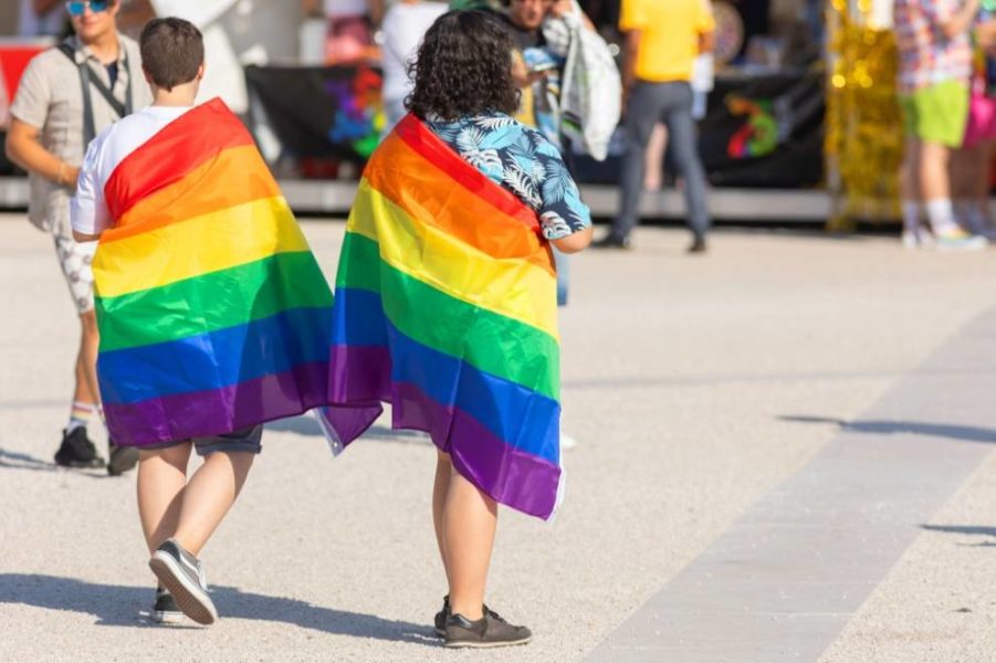 Two people walking while holding a pride flag