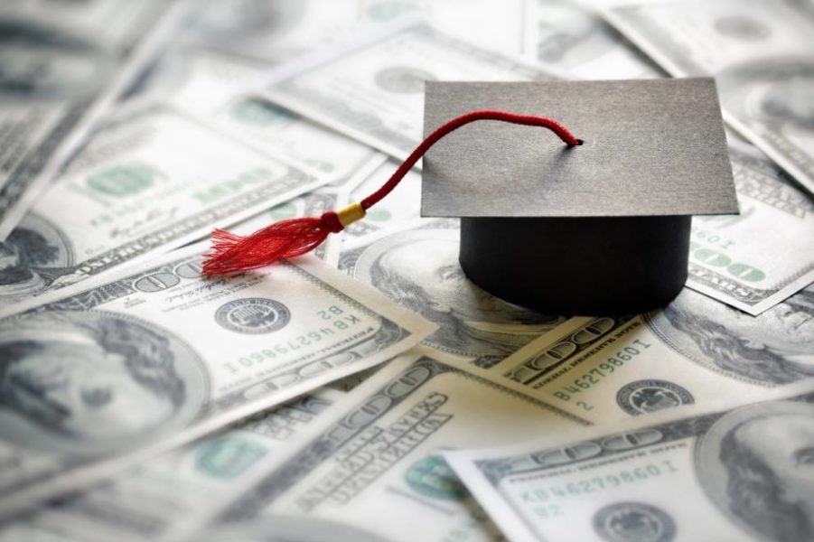 A mortar board placed on spread out dollar notes