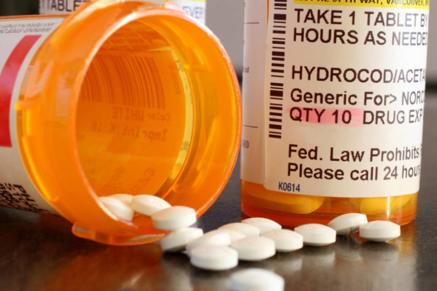 Frasco de pastillas, pastillas derramadas sobre la mesa.