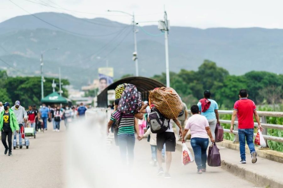Travelers crossing a bridge with bags and luggage