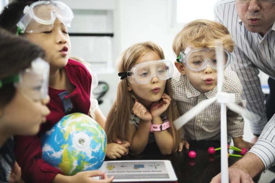 Un grupo diverso de niños y adultos con gafas observando una turbina eólica