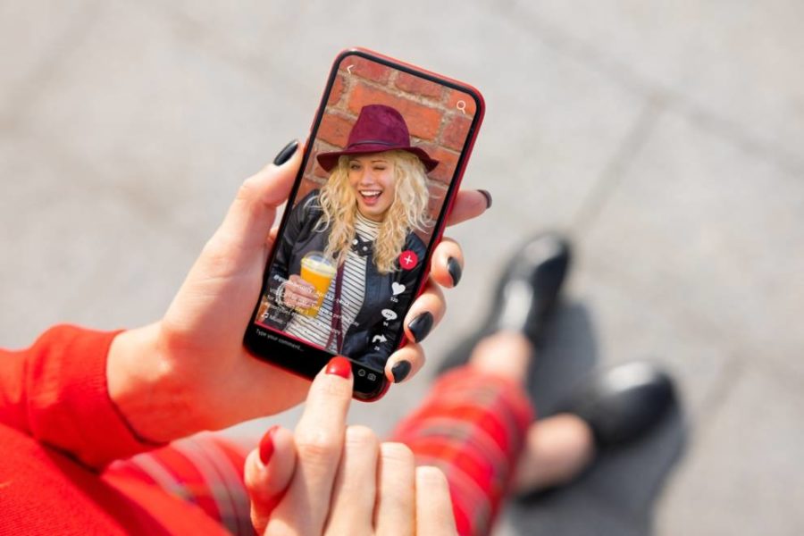 Una mujer sosteniendo un teléfono inteligente mostrando un vídeo de otra mujer en TikTok