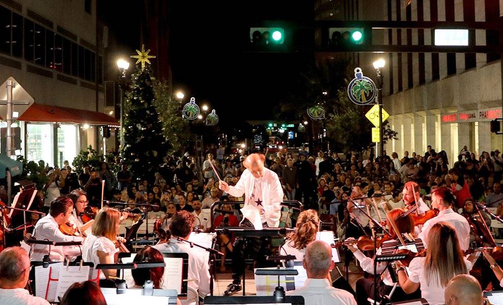 A bustling city street at night filled with a grand orchestra passionately performing their music