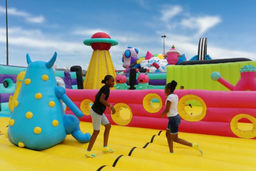 Dos niños recorren alegremente una carrera de obstáculos inflable, llena de obstáculos coloridos y rodeados de una atmósfera vibrante.