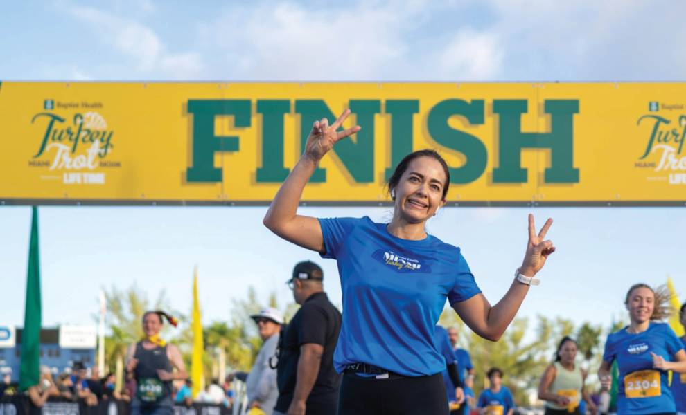 Una mujer corriendo hacia la meta en una carrera, decidida a alcanzar su objetivo en medio de una feroz competencia.