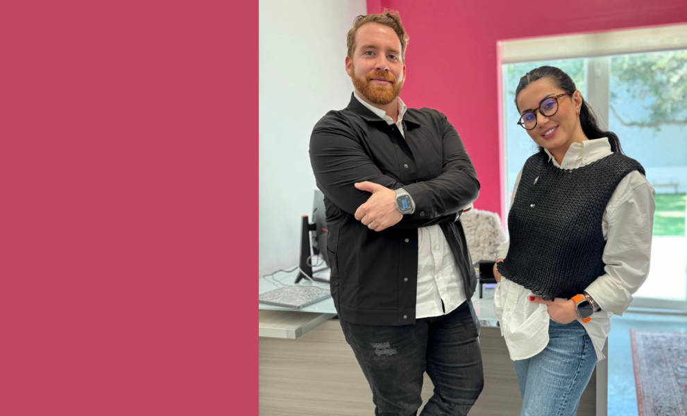 A couple posing in front of a pink wall.