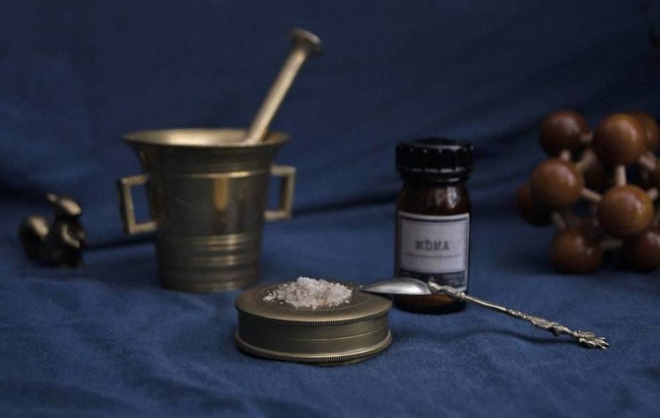 A bottle containing MDMA next to a brass mortar