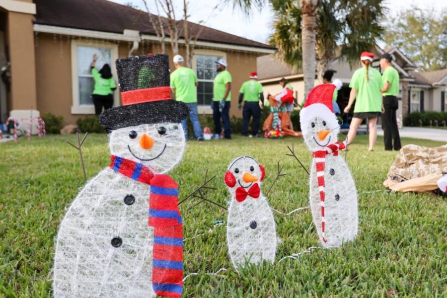 Three paper snowman on grass while work for energy saving is going on background.