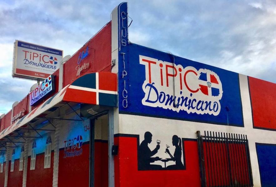 A building with a sign reading "Tipico Dominicanos" - a typical Dominican establishment.